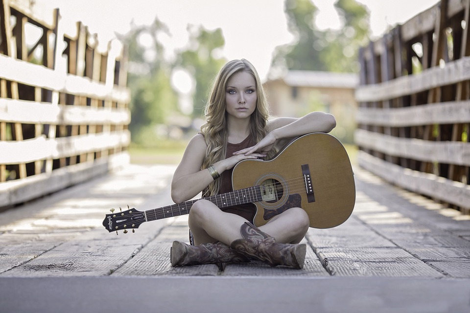 blone girl sitting with an acoustic guitar
